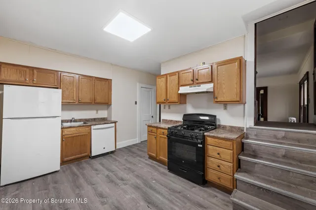 a kitchen with granite countertop wooden floors and stainless steel appliances