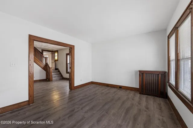 a view of an empty room with wooden floor and a window