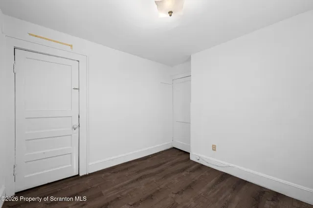 a view of a hallway with wooden floor and a bathroom