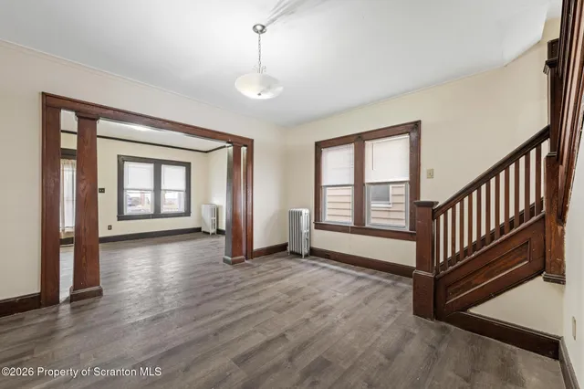 a view of an empty room with wooden floor and a window