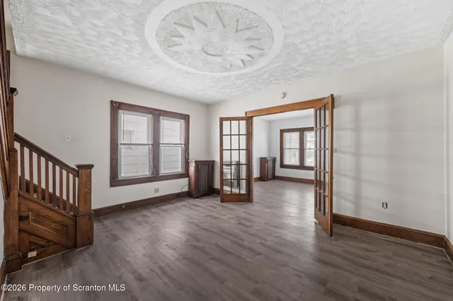 a view of an empty room with wooden floor and a window