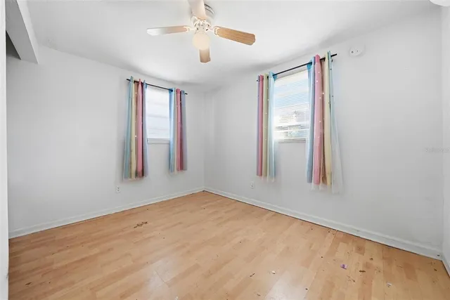 an empty room with windows and fan