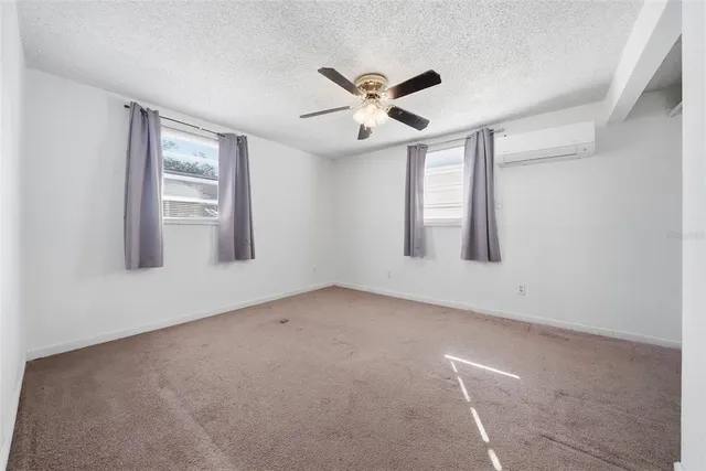 an empty room with windows and fan