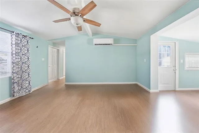 an empty room with wooden floor fan and windows