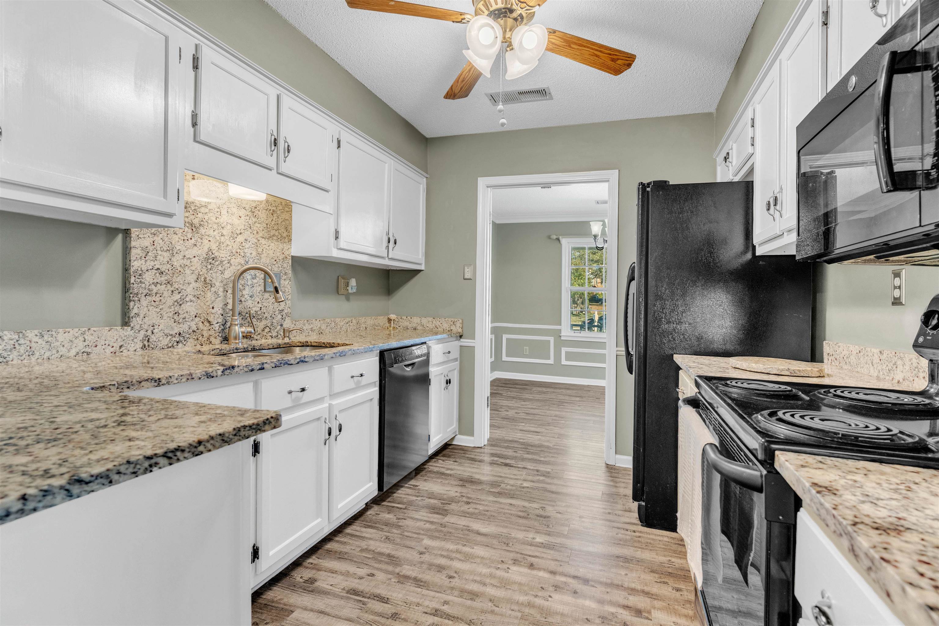 301 East Harpers Ferry Road Collierville, TN 38017 - Photo 6 of 39 Kitchen featuring black appliances, white cabinetry, light wood finished floors, light stone countertops, and a decorative wall