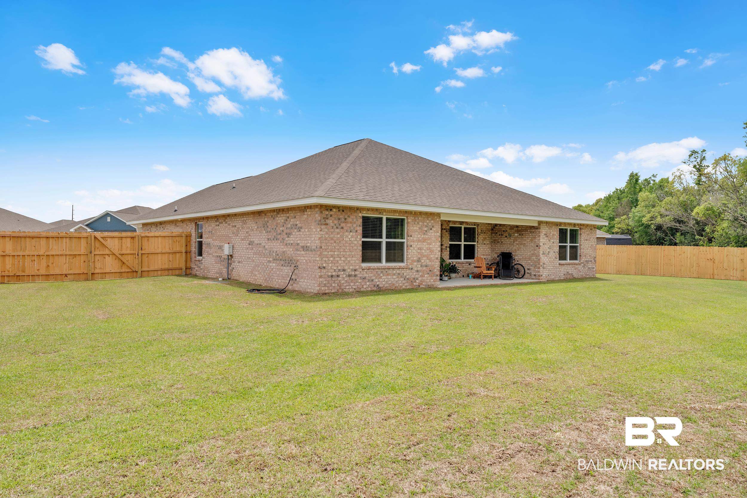 24460 Ringneck Loop Elberta, AL 36530 - Photo 11 of 46 Rear view of property with a lawn, a patio, a fenced backyard, and brick siding