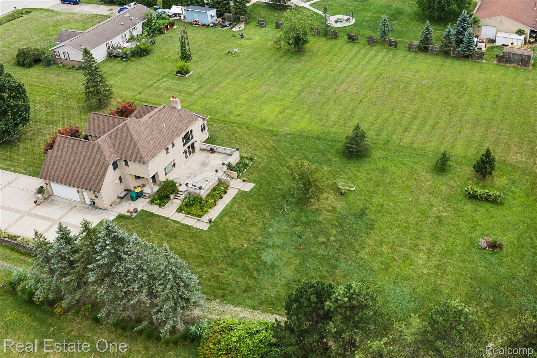 17268 Beech Daly Road Romulus, MI 48174 - Photo 10 of 60 Expansive green lot featuring a multi-story residence with an attached two-car garage, extensive concrete patio, and established landscaping