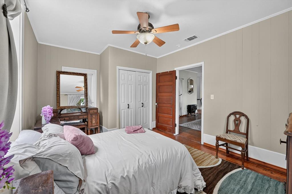 304 East Main Street Itasca, TX 76055 - Photo 27 of 38 Wood-finish flooring, paneled wall detailing, ceiling fan with light fixture, and white bi-fold closet doors