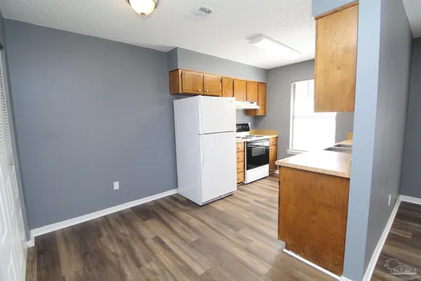 a view of a kitchen with wooden floor and electronic appliances