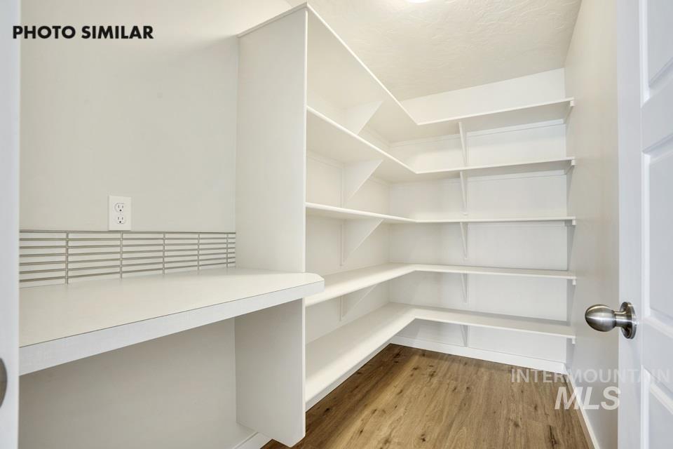 1652 Haystack Road Emmett, ID 83617 - Photo 12 of 29 Spacious pantry featuring extensive white shelving, a built-in countertop, a tile backsplash, and wood-finish flooring
