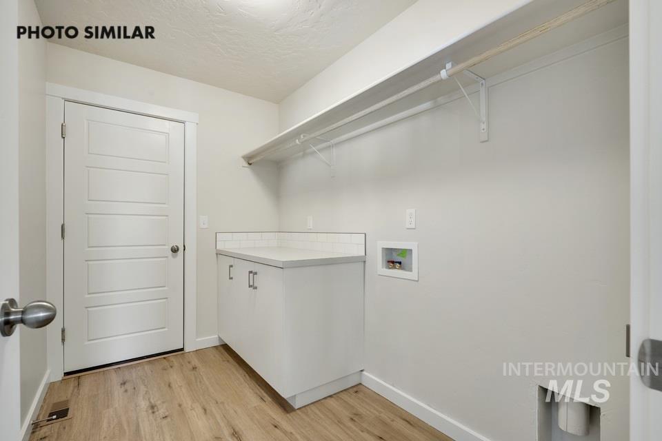 1652 Haystack Road Emmett, ID 83617 - Photo 13 of 29 Dedicated laundry area with wood-finish flooring, white cabinetry, and a white countertop
