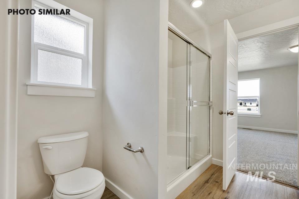 1652 Haystack Road Emmett, ID 83617 - Photo 17 of 29 Bathroom featuring a white toilet, frosted window, and a glass-enclosed shower with a built-in bench