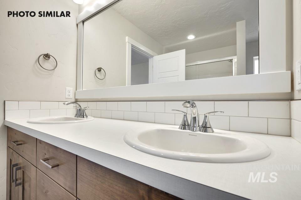 1652 Haystack Road Emmett, ID 83617 - Photo 18 of 29 Double vanity featuring integrated sinks, chrome faucets, wood-finish cabinetry, and a white subway tile backsplash