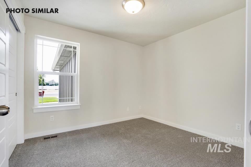 1652 Haystack Road Emmett, ID 83617 - Photo 21 of 29 Bright room featuring a large window with white trim, neutral carpet, white walls, and a flush-mount ceiling light fixture