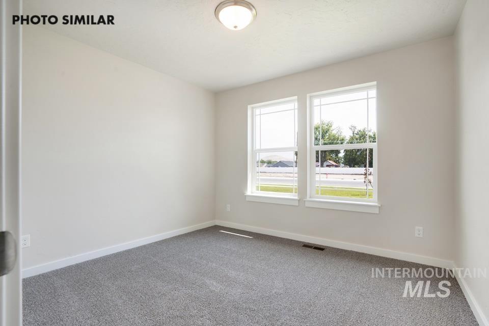 1652 Haystack Road Emmett, ID 83617 - Photo 23 of 29 Spacious room featuring neutral wall paint, gray carpet flooring, two large windows with white trim, and a flush mount ceiling light fixture