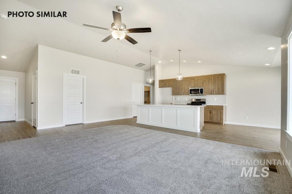 1652 Haystack Road Emmett, ID 83617 - Photo 4 of 29 Open-concept living area featuring a vaulted ceiling with a ceiling fan, light wood-finish flooring, and light gray carpeting