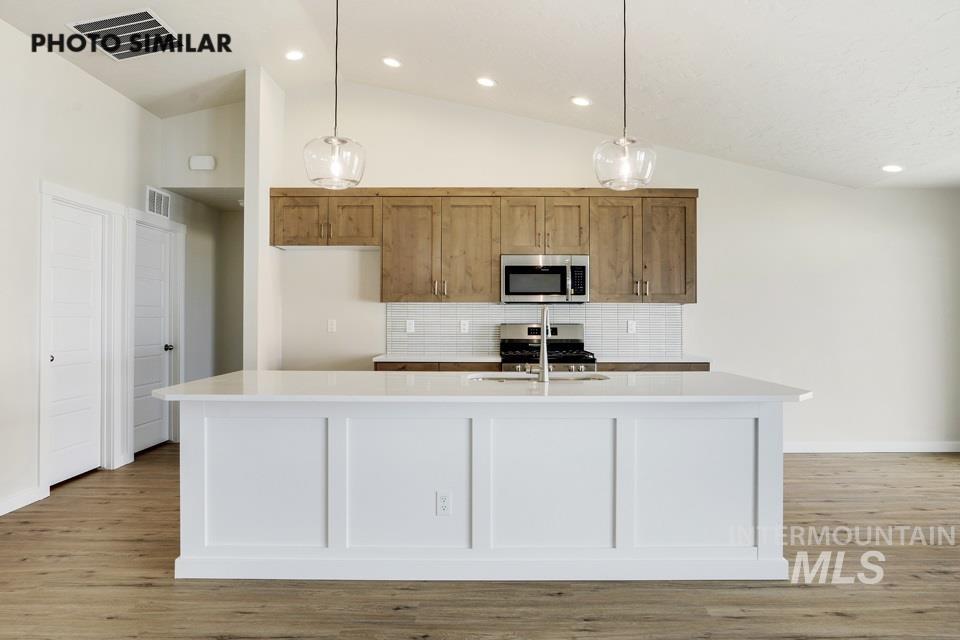 1652 Haystack Road Emmett, ID 83617 - Photo 7 of 29 Kitchen featuring a spacious island with panel detailing, light wood-finish flooring, and vaulted ceilings