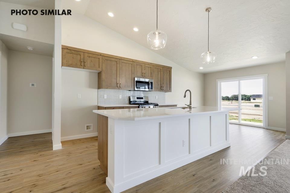 1652 Haystack Road Emmett, ID 83617 - Photo 8 of 29 Kitchen featuring a center island, wood-finish flooring, vaulted ceiling, recessed lighting, and sliding glass doors