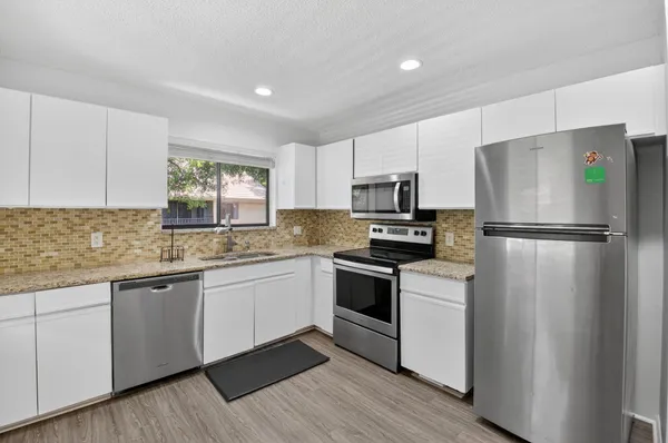 a kitchen with granite countertop stainless steel appliances a refrigerator a sink and a stove