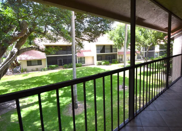 a backyard of a house with table and chairs a large tree