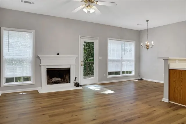 a view of an empty room with wooden floor fireplace and a window