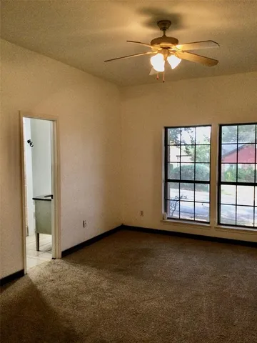 an empty room with a window and a ceiling fan