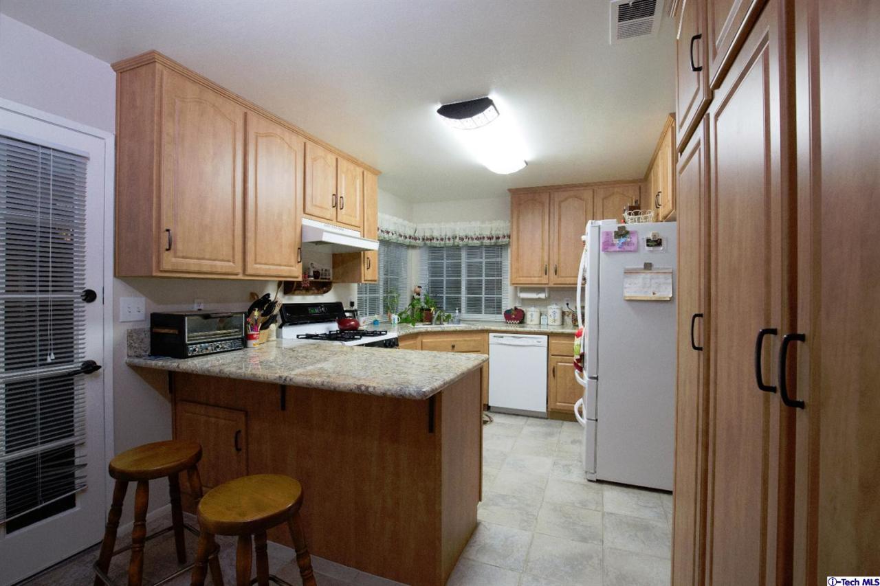25633 Salceda Road Valencia, CA 91355 - Photo 27 of 29 a kitchen with stainless steel appliances granite countertop a refrigerator a sink dishwasher a stove and white cabinets with wooden floor