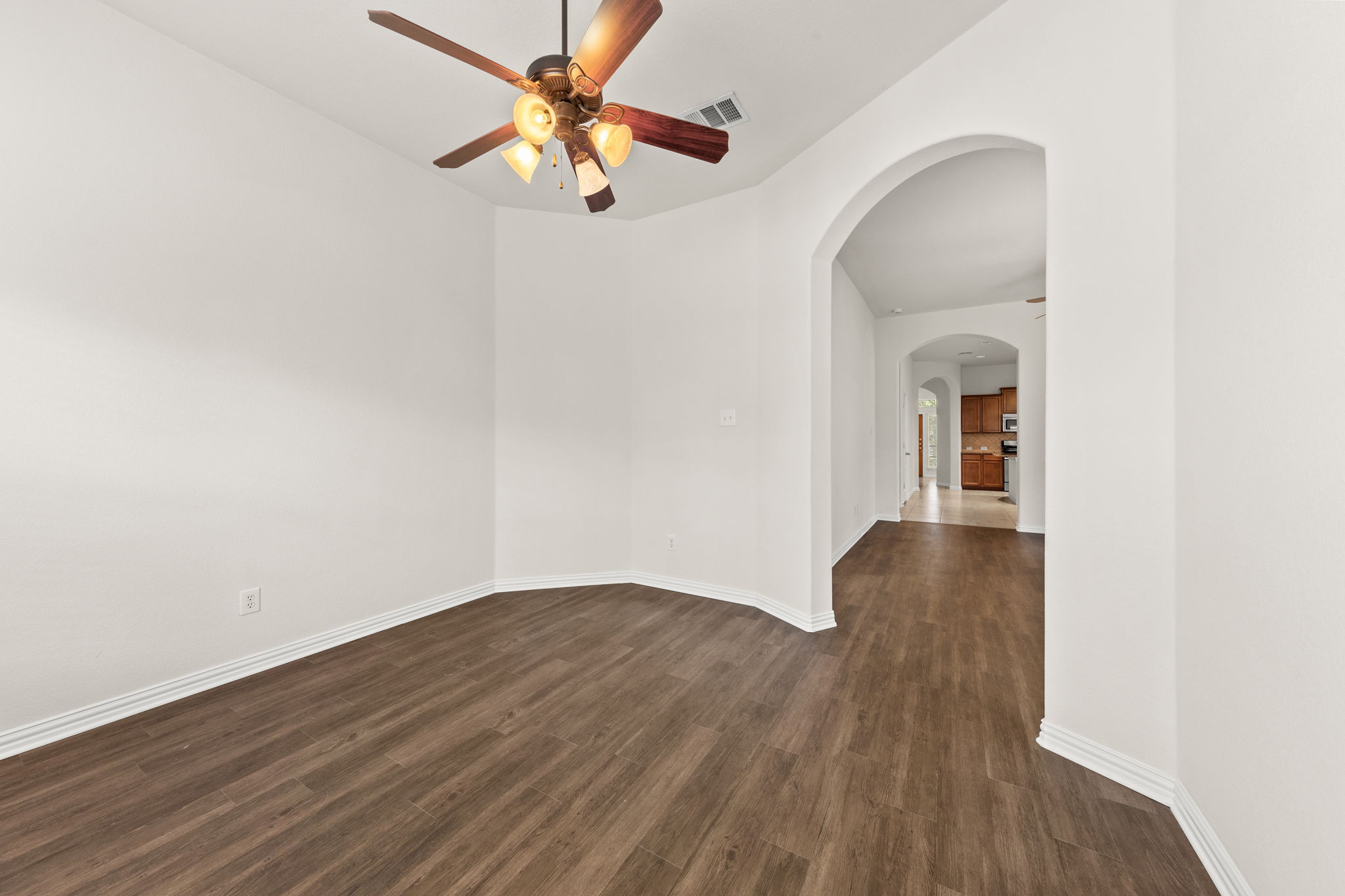 411 Tascate Street Georgetown, TX 78628 - Photo 7 of 41 Hardwood-style flooring and a bright ceiling fan illuminate this spacious interior area, leading to an arched hallway.