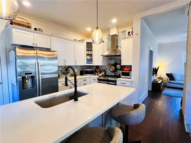 a kitchen with stainless steel appliances kitchen island granite countertop a refrigerator a stove and a sink with wooden floor