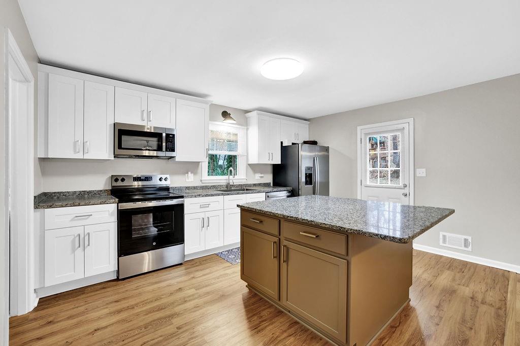 3091 Clifton Road Southeast Smyrna, GA 30080 - Photo 11 of 36 a kitchen with stainless steel appliances granite countertop a stove top oven a sink dishwasher and a refrigerator with wooden floor