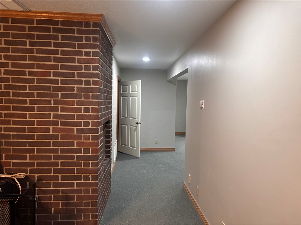 15262 Shipe Road Gravette, AR 72736 - Photo 5 of 60 Brick fireplace structure with wood trim, neutral wall paint, and gray carpeting