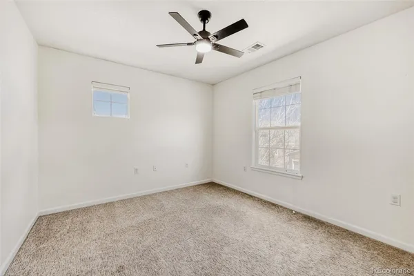 an empty room with windows and fan