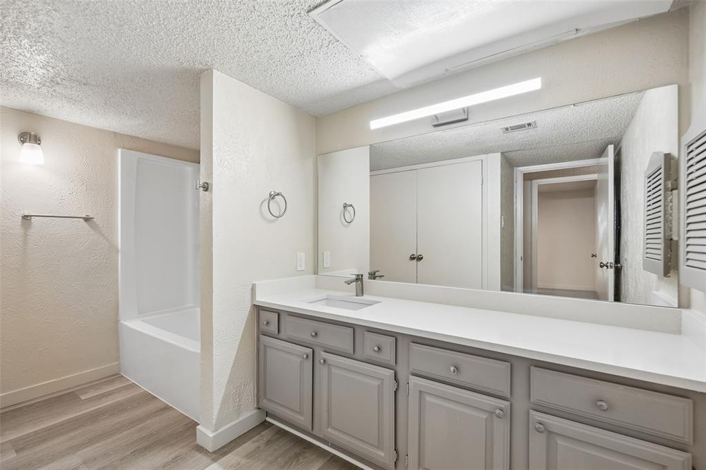 11480 Audelia Road, Unit 136 Dallas, TX 75243 - Photo 28 of 29 Second Bathroom featuring wood-finish flooring, a white bathtub/shower combination, a vanity with grey cabinetry, a white countertop, and an expansive wall-mounted mirror