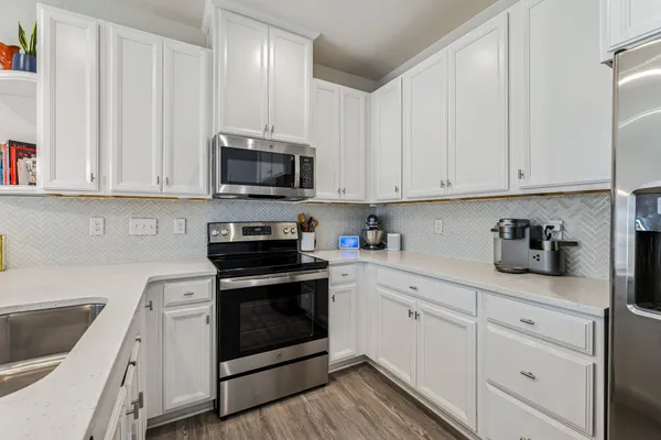 a kitchen with granite countertop white cabinets and stainless steel appliances