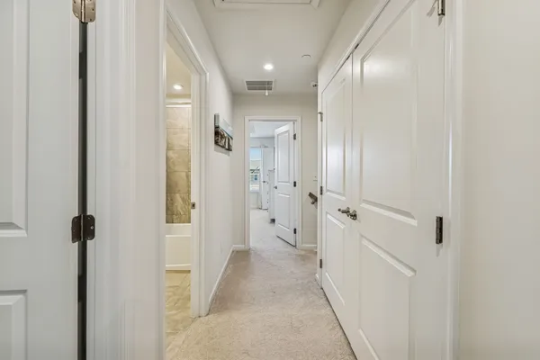 a view of a hallway with wooden floor and a bathroom