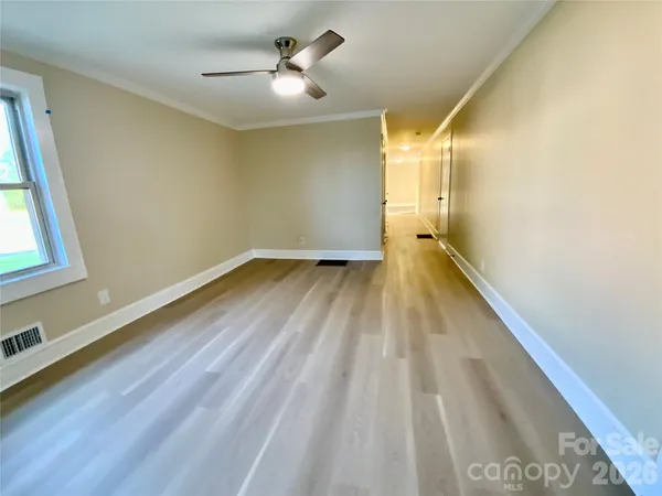 a view of empty room with wooden floor and fan