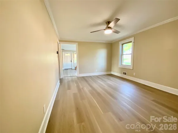a view of an empty room with wooden floor and a window