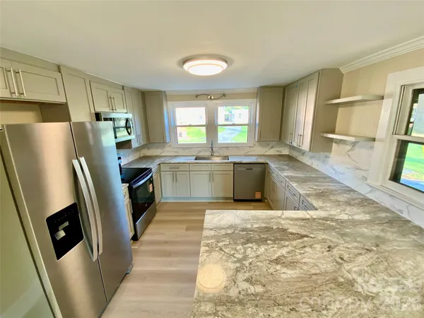 a kitchen with stainless steel appliances granite countertop a refrigerator a sink a stove with island