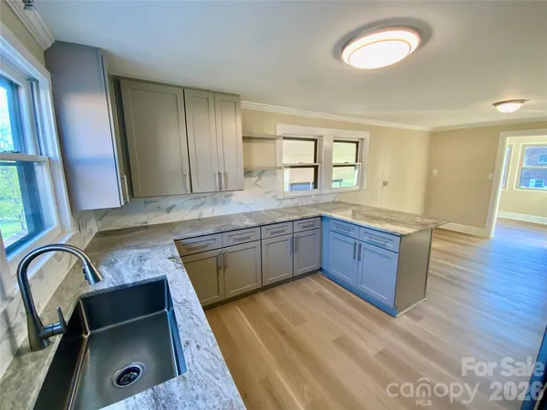 a kitchen with stainless steel appliances granite countertop a sink a stove wooden floor and cabinets