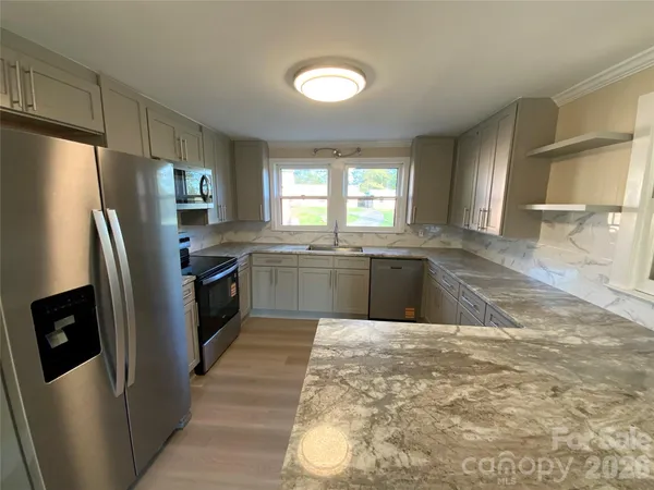 a kitchen with stainless steel appliances granite countertop a sink a stove a refrigerator with grey cabinets