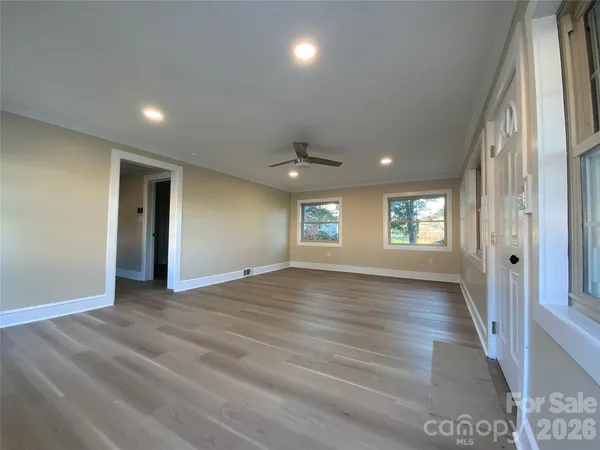 an empty room with wooden floor and windows