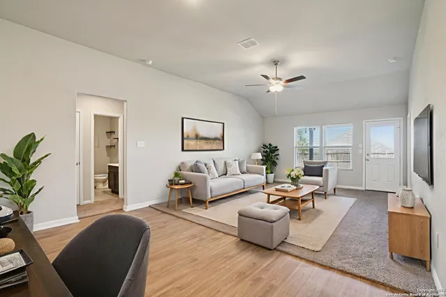 a living room with furniture a rug potted plant and a window