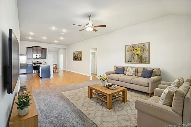 a living room with furniture kitchen view and a flat screen tv