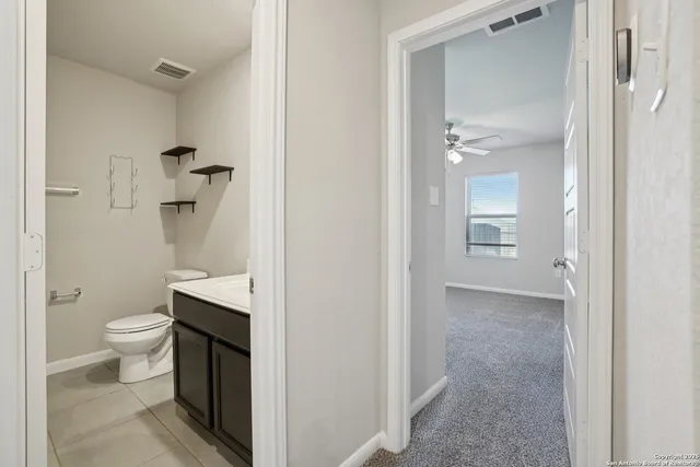 an empty room with a chandelier fan and windows