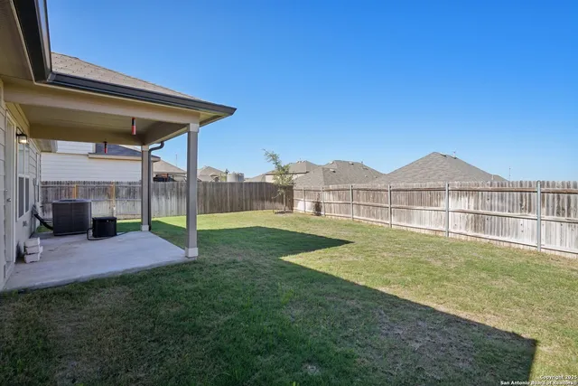 a view of a house with a big yard plants and large tree