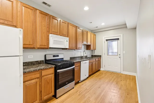 a large kitchen with stainless steel appliances granite countertop a stove a sink and a refrigerator