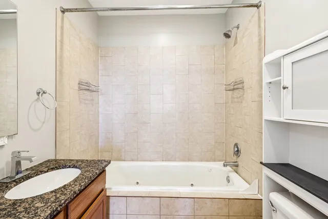 a bathroom with a granite countertop bathtub shower sink and vanity