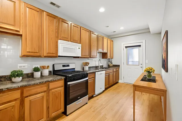 a kitchen with stainless steel appliances granite countertop wooden cabinets a stove top oven with wooden floor