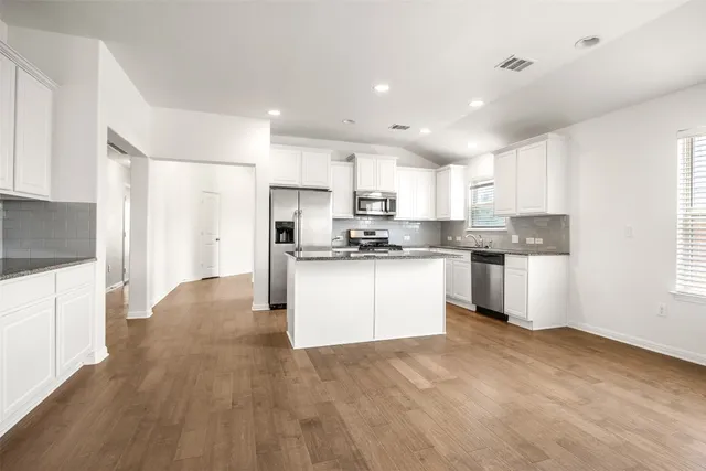 a kitchen with granite countertop white cabinets and stainless steel appliances