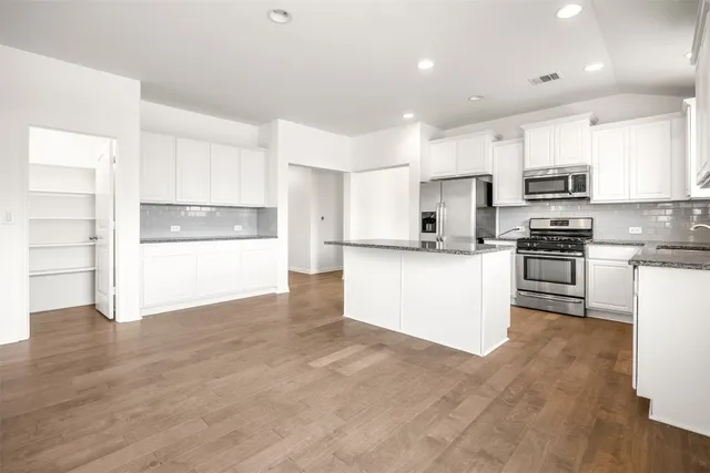 a view of kitchen with granite countertop a stove top oven a sink and white cabinets